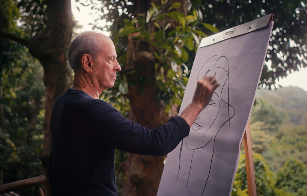 Cena do filme Singulares com Ney Matogrosso desenhando na sua casa